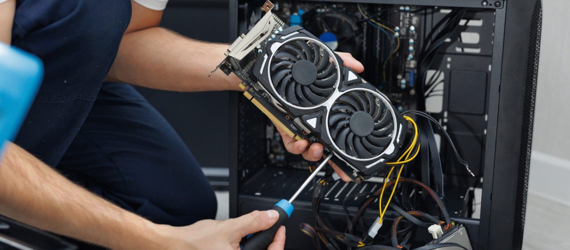 Man is holding a computer video card in his hands. Computer maintenance.